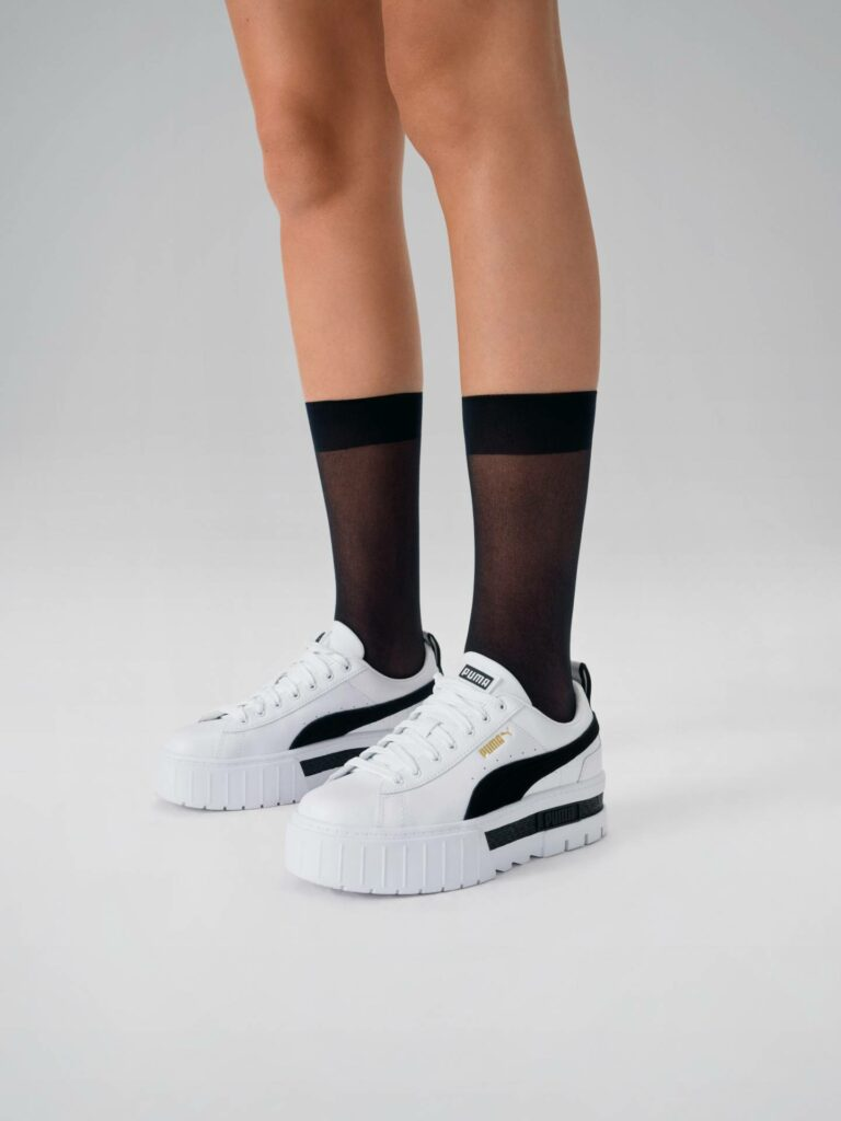 Bílé tenisky Puma na platformě a černé punčochové ponožky
